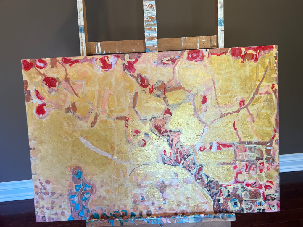 An abstract painting on canvas displayed on an easel :The artwork features a textured gold background with splashes of red, pink, blue, and brown, and is photographed against a dark background.